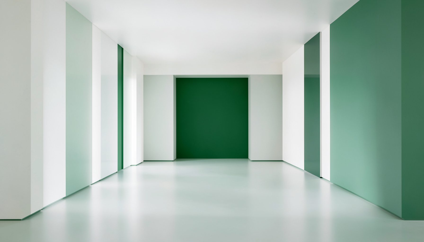 Fotografía arquitectónica de un espacio interior simétrico en tonos blancos y verdes suaves, de aspecto sereno