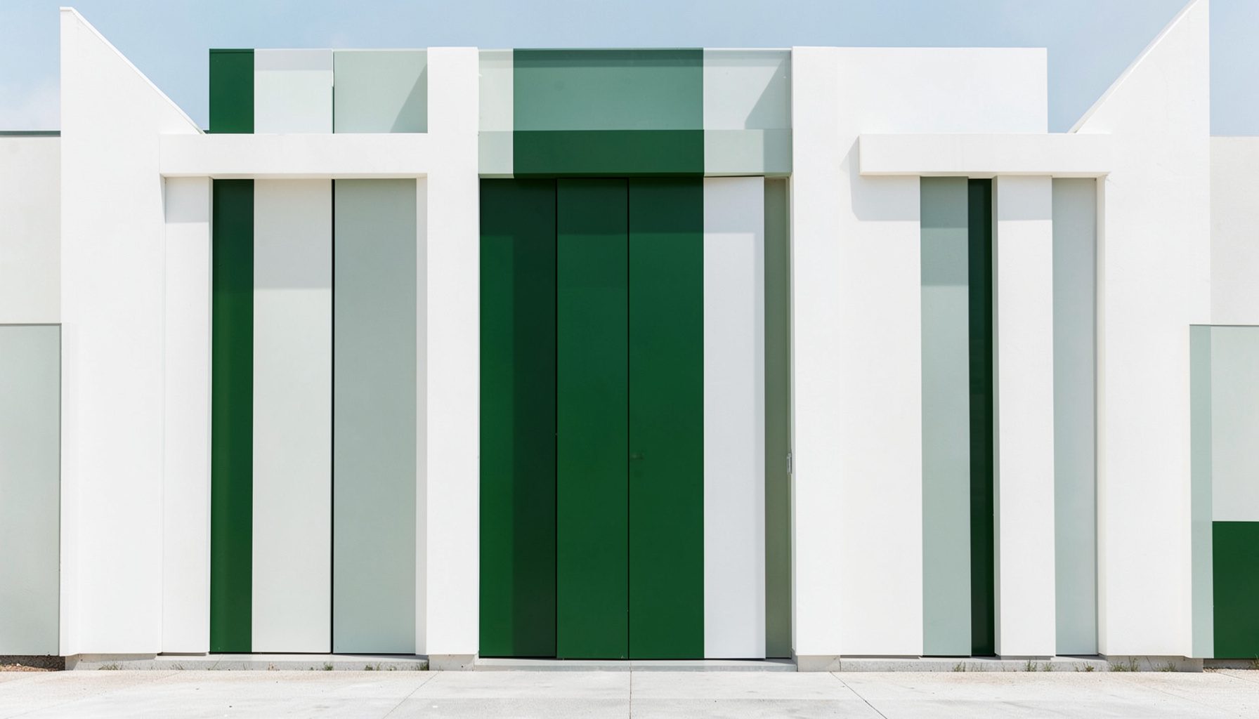 Fotografía de una fachada simétrica blanca con acentos verde oliva, estilo limpio y ordenado