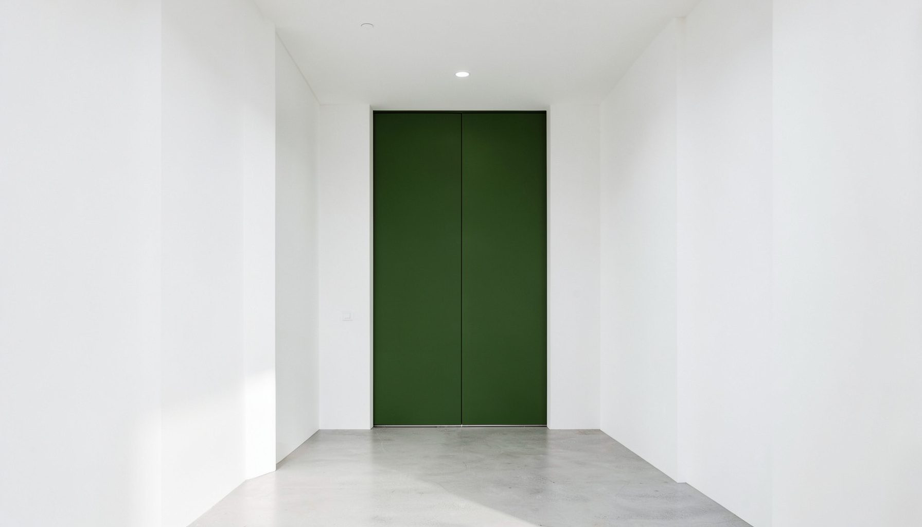 Fotografía simétrica de una entrada de estilo minimalista en blanco con detalles en verde oliva y luz natural suave